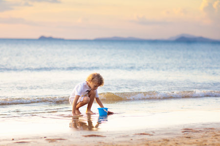 Child playing on tropical beach. Little boy at sea shore. Family summer vacation. Kids play with water and sand toys. Ocean and island fun. Travel with young children in Asia.の写真素材