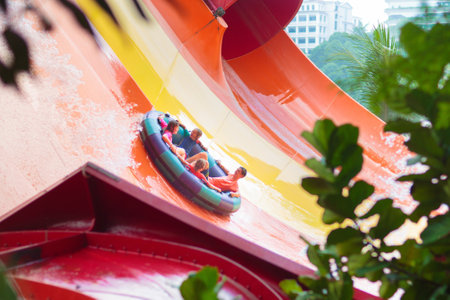 Kids on water slide in outdoor swimming pool. Family in aqua theme park. Children have fun in splash...