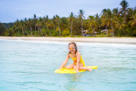 Child surfing on tropical beach. Family summer vacation in Asia. Kids swim in ocean water. Kid on...