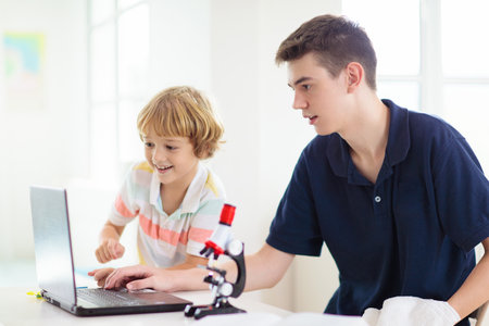 School kids with microscope. Science class. Children making biology or chemistry experiment with...
