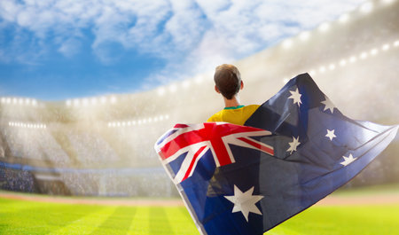 Australia fans on stadium. Australian supporters. Crowd cheering for Aussie football or cricket team victory. Soccer match on outdoor pitch. Patriotic party with national flag and jersey.の写真素材