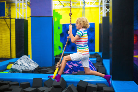 Child jumping in trampoline park. Bounce fun on kids birthday party. Indoor playground with bouncing castle. Healthy activity for children. Fit kid exercising and playing on colorful trampolines.の写真素材