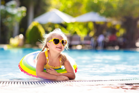 Child with goggles in swimming pool. Little girl learning to swim and dive in outdoor pool of tropical resort. Swimming with kids. Healthy sport activity for children. Sun protection. Water fun.の写真素材