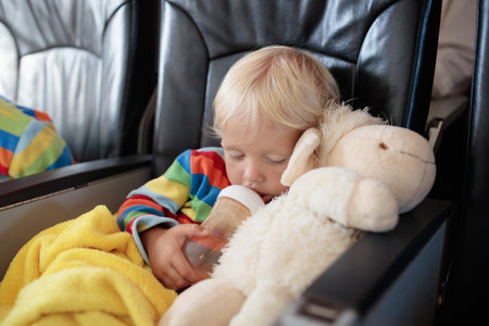 Child in airplane. Kid in air plane sitting in window seat. Flight entertainment for kids. Traveling with young children. Kids fly and travel. Family summer vacation. Little boy with toy in airplane.の写真素材