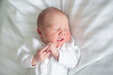 Newborn baby in hospital room on nursing pillow. New born child in crib. Hungry infant in bedside bassinet. Little boy just after birth after bath and examination.の写真素材