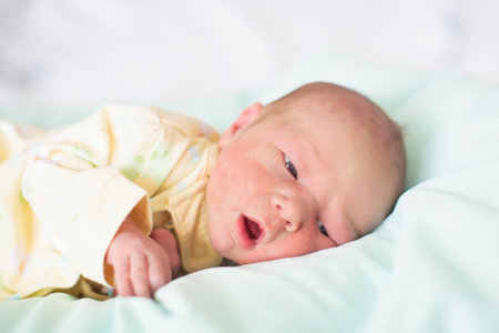 Newborn baby in hospital room on nursing pillow. New born child in crib. Hungry infant in bedside bassinet. Little boy just after birth after bath and examination.の写真素材