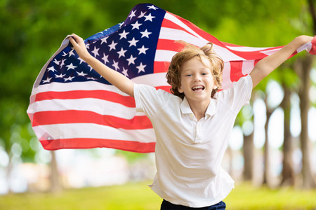 Happy 4th of July. USA supporter with national flag. Happy child celebrating Independence Day.  American fan. US fans on soccer pitch watching team play. Excited kid cheering for America.の写真素材