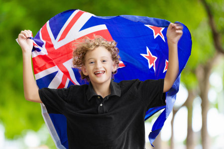 Child running with New Zealand flag. Little New Zealander boy cheering for country team. Kiwi fans on sports pitch watching team play. Family celebrating national day. Championship game.の写真素材