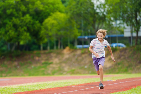 Kids long jump athletics training. Child jumping in sand pit on school stadium. Healthy outdoor exercise for children. Young athlete exercising. Sport for young boy.の写真素材