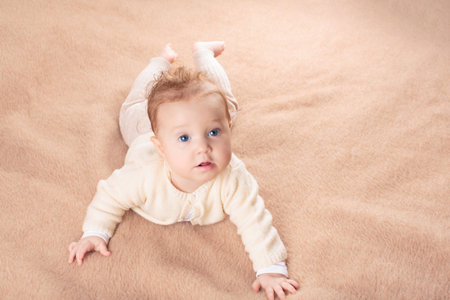 Adorable baby in white sunny bedroom. Newborn child relaxing in bed. Nursery for young children....