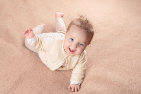 Adorable baby in white sunny bedroom. Newborn child relaxing in bed. Nursery for young children. Textile and bedding for kids. Family morning at home. New born kid during tummy time with toy bear.の写真素材