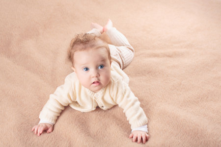 Adorable baby in white sunny bedroom. Newborn child relaxing in bed. Nursery for young children. Textile and bedding for kids. Family morning at home. New born kid during tummy time with toy bear.の写真素材