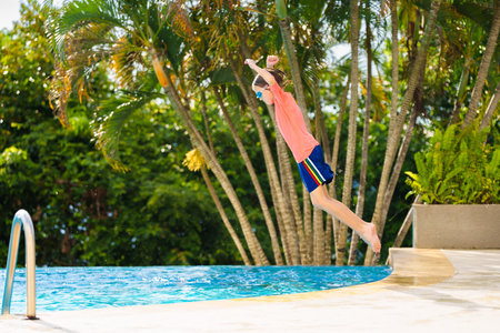Group of kids jump into swimming pool. Summer water fun. Children play in outdoor pool. Summer...