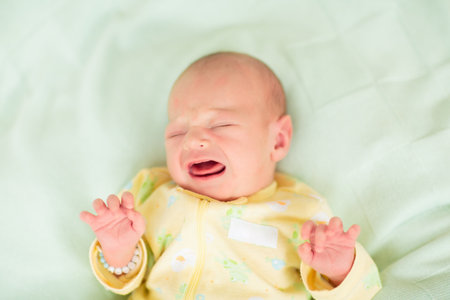 Adorable baby in white sunny bedroom. Newborn child relaxing in bed. Nursery for young children....