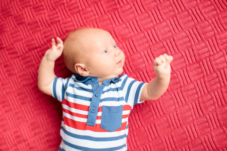 Adorable baby on knitted colorful blanket in white sunny bedroom. Newborn child relaxing in bed....