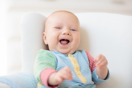 Adorable baby in white rocking chair. Newborn child relaxing in bed. Nursery for young children. Textile and bedding for kids. Family morning at home. New born kid during tummy time with toy bear.の写真素材