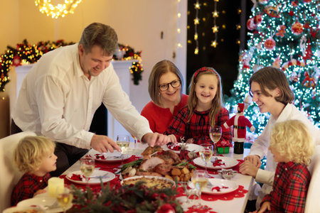 Family with children eating turkey Christmas dinner at fireplace and decorated Xmas tree. Parents, grandparents and children at festive meal. Winter holidays celebration and food. Kids open presents.の写真素材