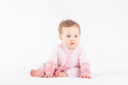 Adorable baby in white sunny bedroom. Toddler girl on white background. Nursery for young children. Textile and bedding for kids. Family morning at home. New born kid.の写真素材