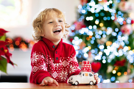 Child with Christmas present. Kid with Xmas gift. Little boy playing with a toy car under Christmas tree. Decorated home for winter holidays. Celebration with children. Kids play.の写真素材