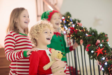 Kids running stairs on Christmas morning. Children in pajamas run downstairs eager to open Xmas presents. Celebration at home. Winter family holiday. Boy and girl opening gifts.の写真素材