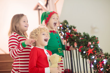Kids running stairs on Christmas morning. Children in pajamas run downstairs eager to open Xmas presents. Celebration at home. Winter family holiday. Boy and girl opening gifts.の写真素材