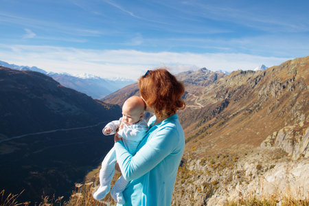 Family with kids hiking in the mountains. Young mother and children hike in beautiful Alps mountain landscape. Travel with baby. Trekking and camping with young child. Outdoor adventure.の写真素材