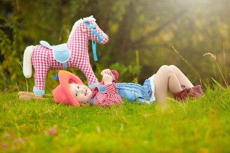 Little boy and girl dressed up as cowboy and cowgirl playing with toy rocking horse in park. Kids play outdoors. Children in Halloween costumes at trick or treat. Toys for preschooler or toddler childの写真素材