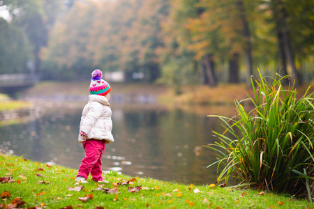 Kids play in autumn park. Children throwing yellow and red leaves. Little girl with oak and maple leaf. Fall foliage. Family outdoor fun in autumn. Toddler kid or preschooler child in fall.の写真素材