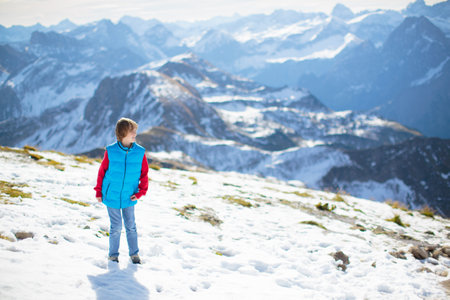 Family with kids hiking in the mountains. Young mother and children hike in beautiful Alps mountain landscape. Travel with baby. Trekking and camping with young child. Outdoor adventure.の写真素材