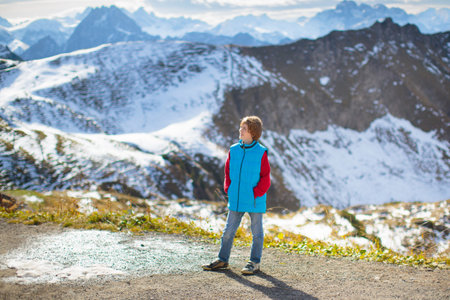 Family with kids hiking in the mountains. Young mother and children hike in beautiful Alps mountain landscape. Travel with baby. Trekking and camping with young child. Outdoor adventure.の写真素材