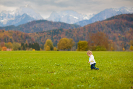 Family with kids hiking in the mountains. Young mother and children hike in beautiful Alps mountain landscape. Travel with baby. Trekking and camping with young child. Outdoor adventure.の写真素材