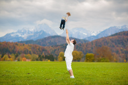 Family with kids hiking in the mountains. Young mother and children hike in beautiful Alps mountain landscape. Travel with baby. Trekking and camping with young child. Outdoor adventure.の写真素材
