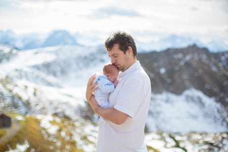 Family with kids hiking in the mountains. Young mother and children hike in beautiful Alps mountain landscape. Travel with baby. Trekking and camping with young child. Outdoor adventure.の写真素材