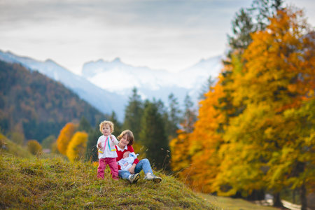 Family with kids hiking in the mountains. Young children hike in beautiful Alps mountain landscape. Travel with baby. Trekking and camping with young child. Outdoor adventure.の写真素材