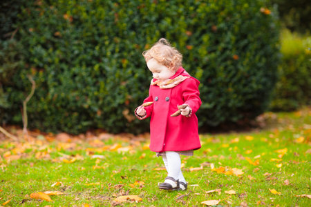 Happy children playing in beautiful autumn park on warm sunny fall day. Kids play with golden maple leaves.の写真素材