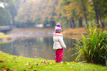 Kids play in autumn park. Children throwing yellow and red leaves. Little girl with oak and maple leaf. Fall foliage. Family outdoor fun in autumn. Toddler kid or preschooler child in fall.の写真素材