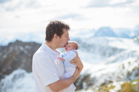 Family with kids hiking in the mountains. Young mother and children hike in beautiful Alps mountain landscape. Travel with baby. Trekking and camping with young child. Outdoor adventure.の写真素材