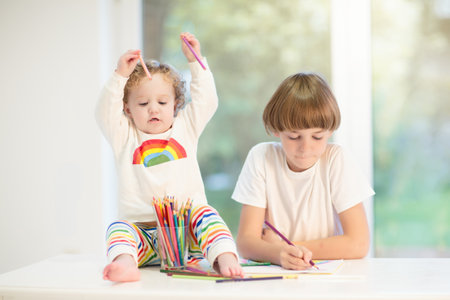 Kids paint. Child painting in white sunny study room. Little girl drawing rainbow. School kid doing art homework. Arts and crafts for kids. Paint on children's hands. Creative little artist at work.の写真素材