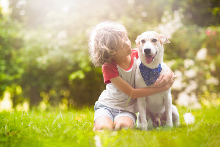 Child playing with a dog in sunny summer garden. Kid walking puppy. Kids and pets. Animal love and...