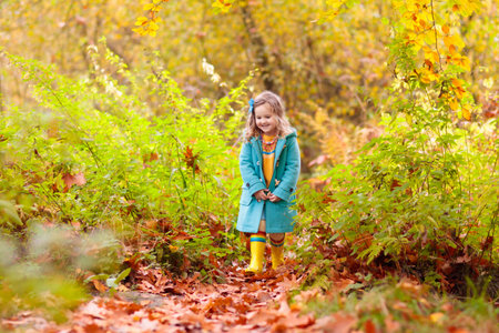 Happy children playing in beautiful autumn park on warm sunny fall day. Kids play with golden maple leaves.の写真素材