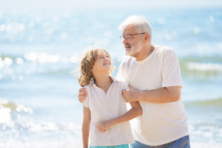 Grandfather and kids play on summer beach. Family day outdoor. Grandparent and grandchildren travel to sea side. Generation love. Active senior man playing with grandson. Happy fit retirement.の写真素材