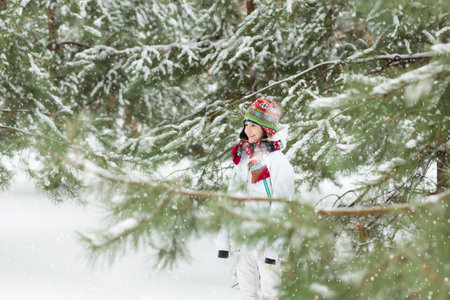 Kids play in snow in winter park. Children playing outdoors on snowy cold day. Boy and girl have fun on sleigh ride. Christmas vacation activity. Outdoor fun by winter weather. Travel with child.の写真素材