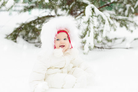 Kids play in snow in winter park. Children playing outdoors on snowy cold day. Boy and girl have fun on sleigh ride. Christmas vacation activity. Outdoor fun by winter weather. Travel with child.の写真素材