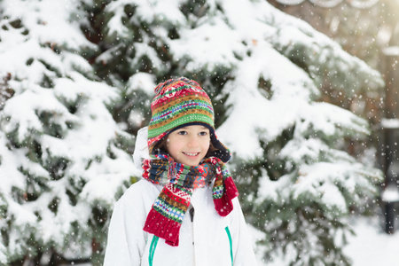 Kids play in snow in winter park. Children playing outdoors on snowy cold day. Boy and girl have fun on sleigh ride. Christmas vacation activity. Outdoor fun by winter weather. Travel with child.の写真素材