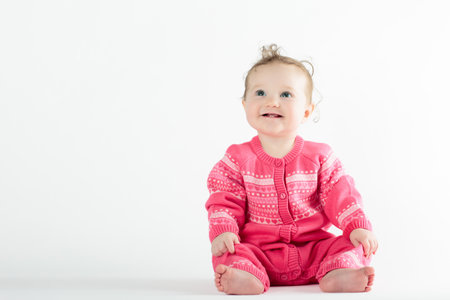 Adorable baby in white sunny bedroom. Newborn child relaxing in bed. Nursery for young children. Textile and bedding for kids. Family morning at home. New born kid during tummy time.の写真素材