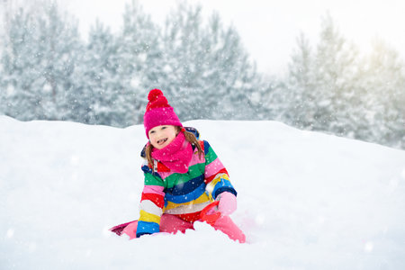 Little girl enjoying a sleigh ride. Child sledding. Toddler kid riding a sledge. Children play outdoors in snow. Kids sled in the Alps mountains in winter. Outdoor fun for family Christmas vacation.の写真素材