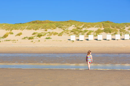 Kids playing on tropical beach. Water splash fun. Little boy splashing in sea waves. Children swim and play on summer family vacation. Sand and water toy, sun protection for young child.の写真素材
