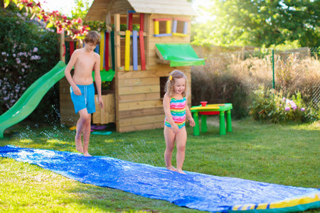 Children playing in inflatable baby pool. Kids swim and splash in colorful garden play center. Happy boy and girl playing with water toys on hot summer day. Family having fun outdoors in the backyard.の写真素材