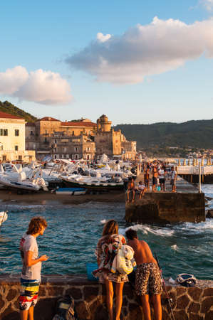 There are many people around tonight in the small town of the south of Italy. At sunset all boats have returned Already in the small harbor. The sea is rough, the air is still very hot. The palace of the Prince Seems To greet the sun sinking into the sea.のeditorial素材
