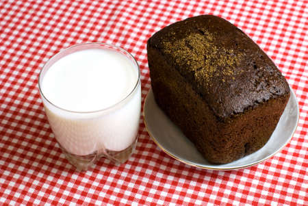 breakfast of a cup of milk, black bread on a red tablecloth の写真素材